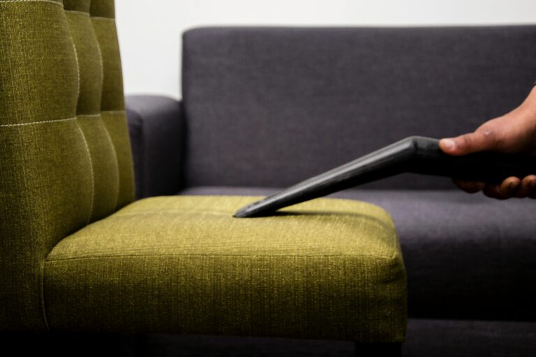 Close-up of a person vacuuming a modern sofa chair indoors, highlighting cleaning service.